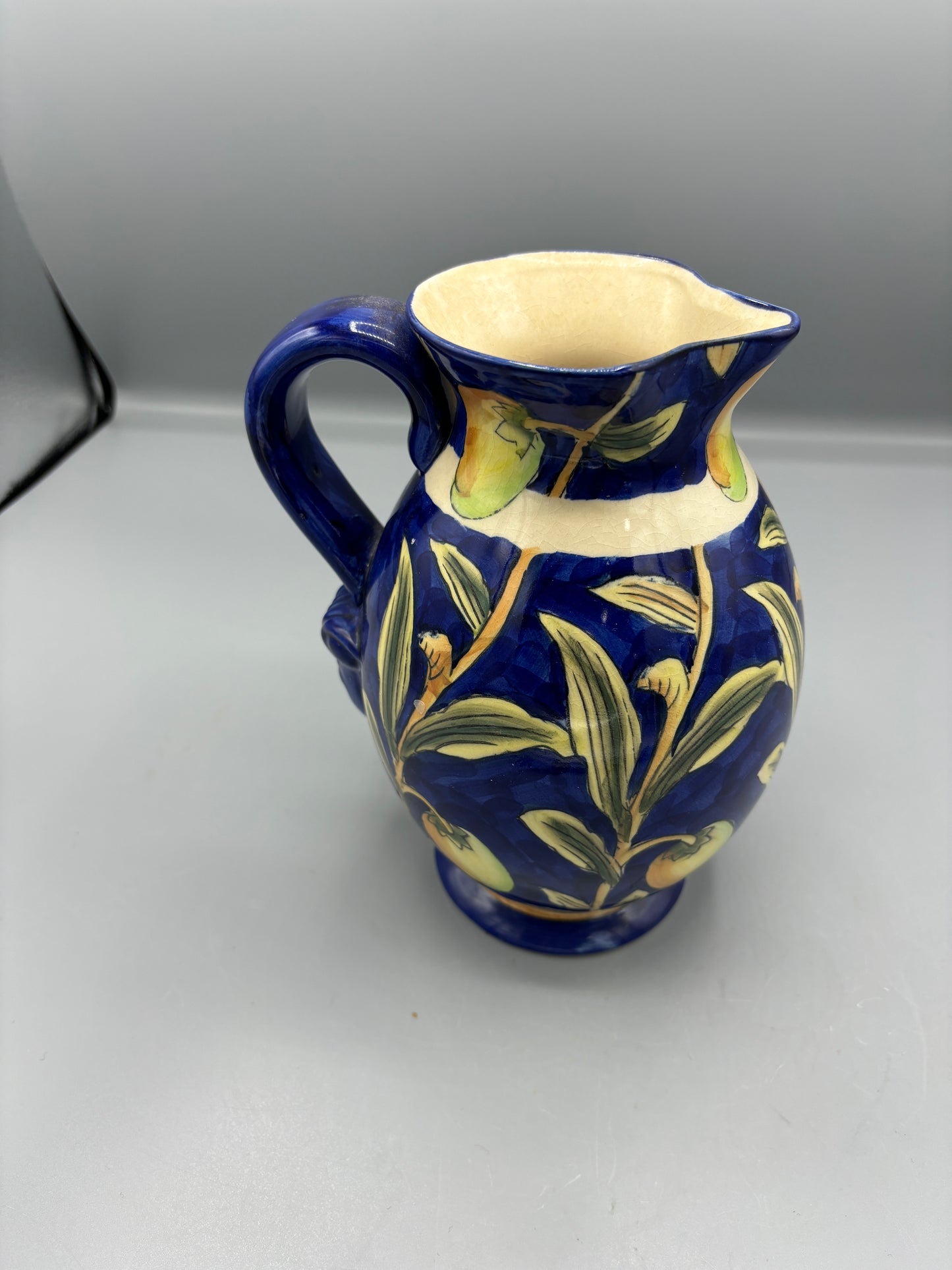 Blue glazed ceramic pitcher with yellow olive fruit