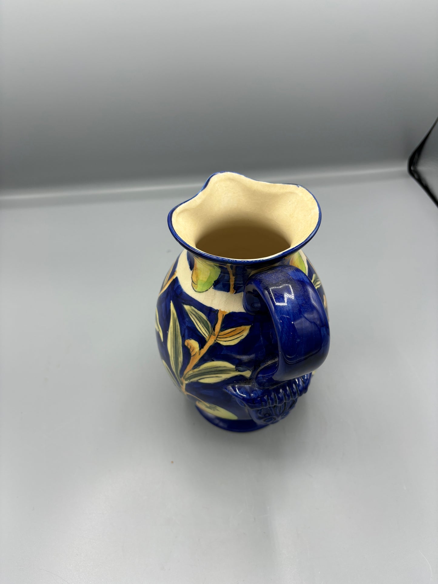 Blue glazed ceramic pitcher with yellow olive fruit