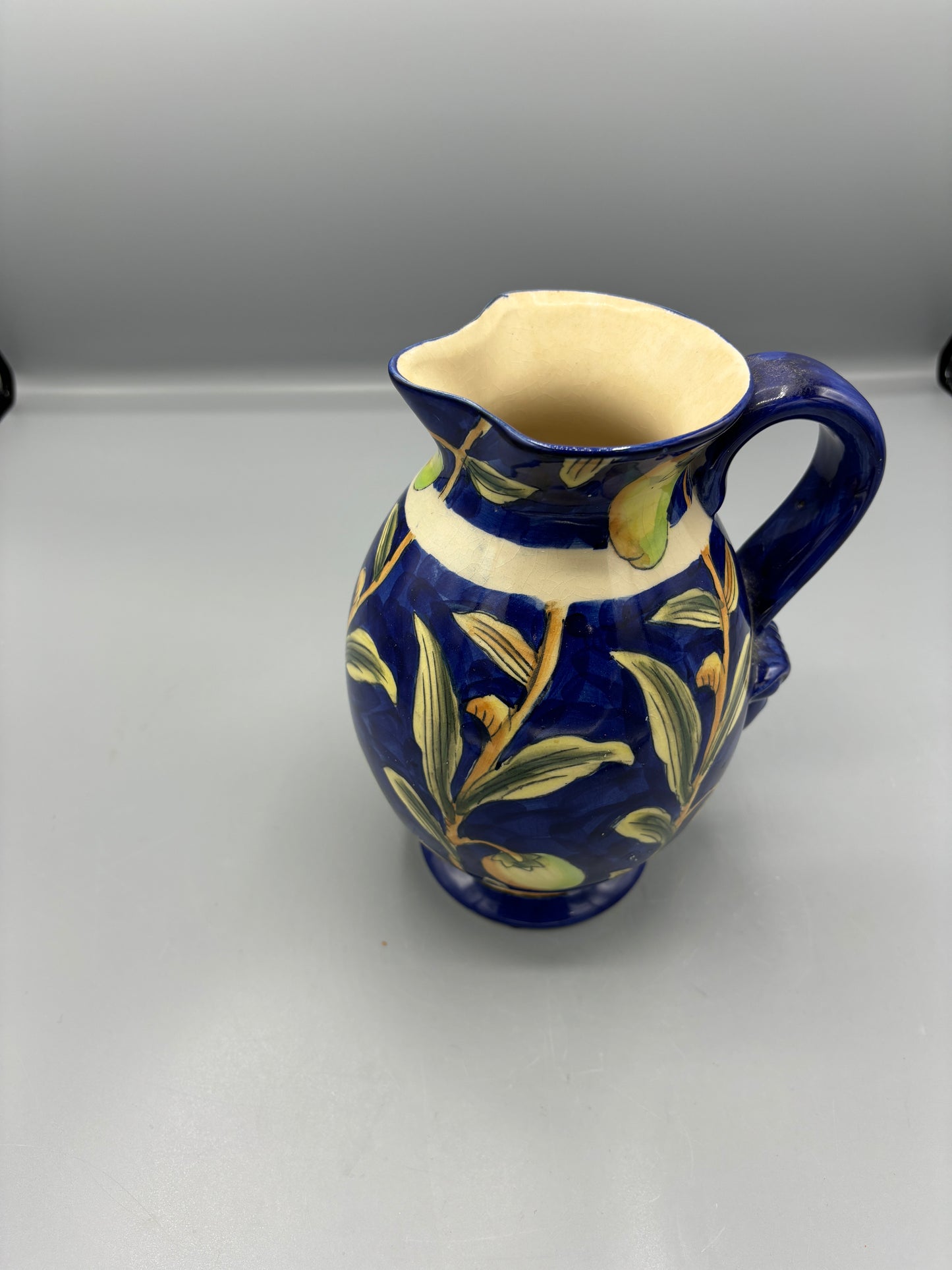 Blue glazed ceramic pitcher with yellow olive fruit