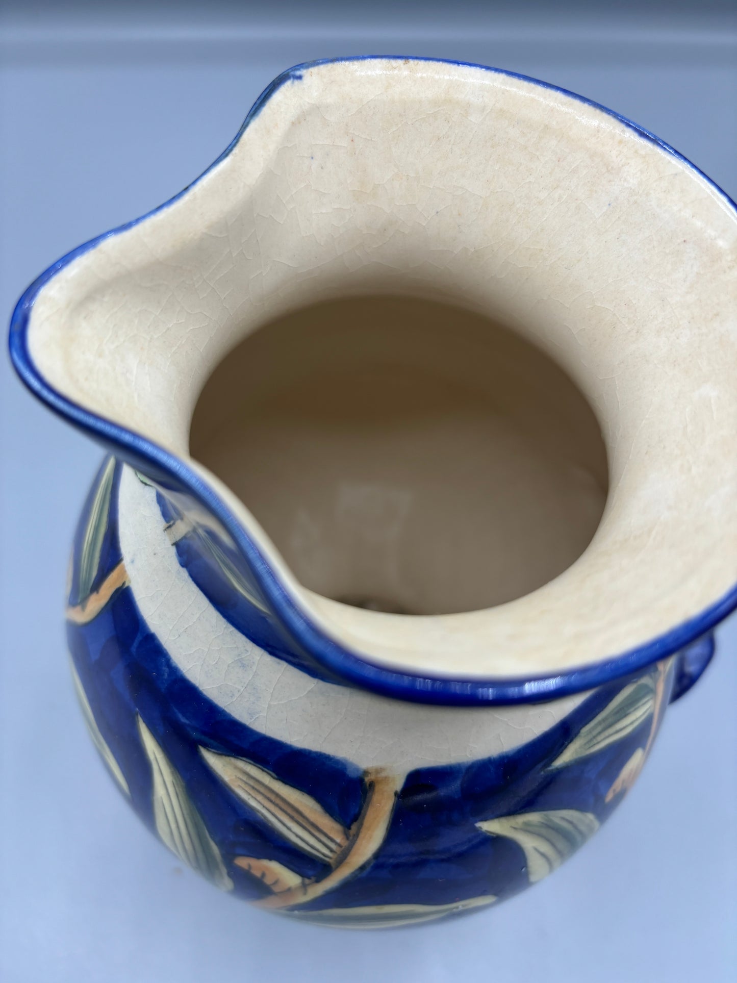 Blue glazed ceramic pitcher with yellow olive fruit