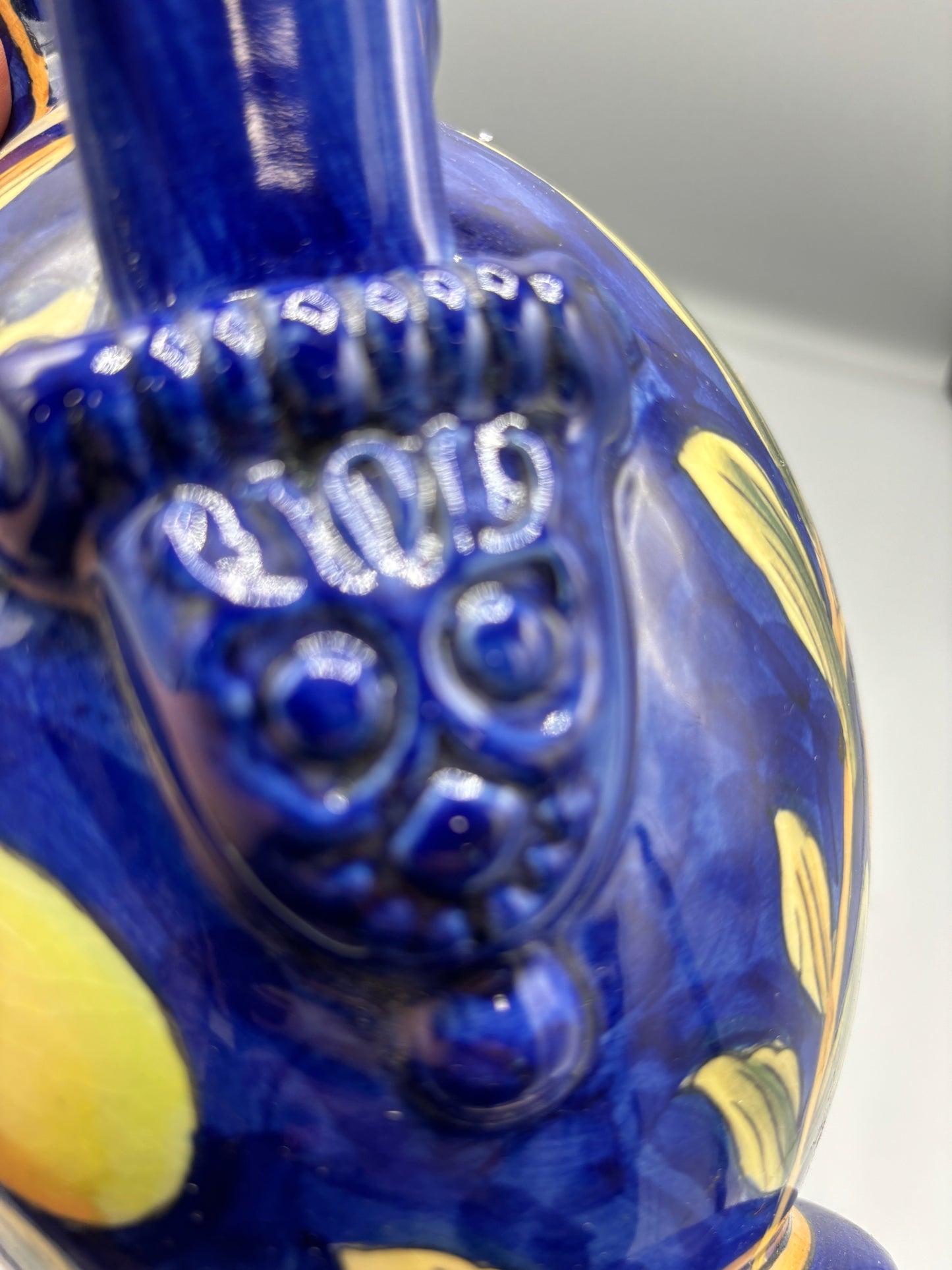 Blue glazed ceramic pitcher with yellow olive fruit